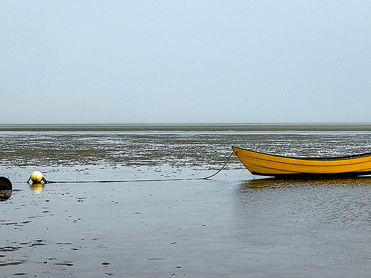 Row boat stranded on the beach at low tied