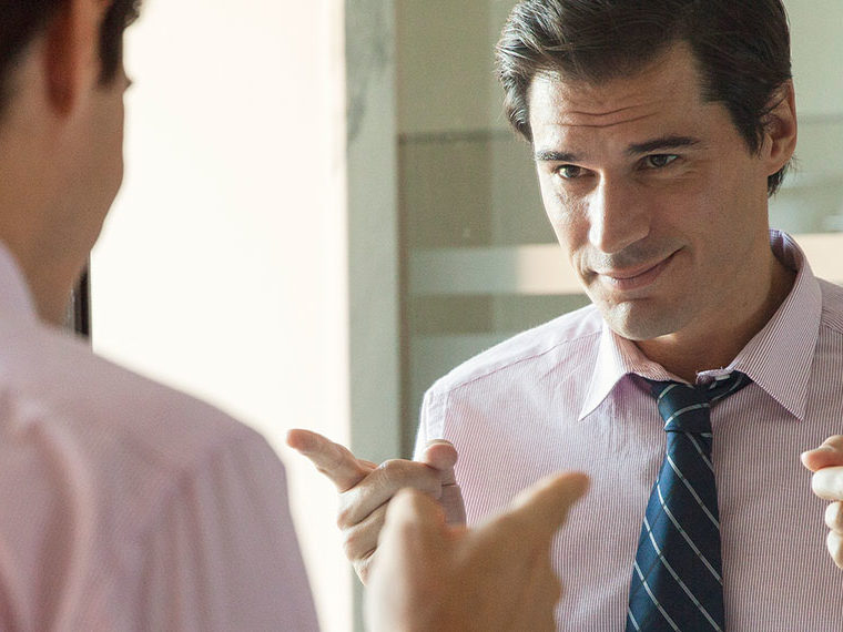 A man dressed in pink dress shirt and tie pointing at himself in the mirror
