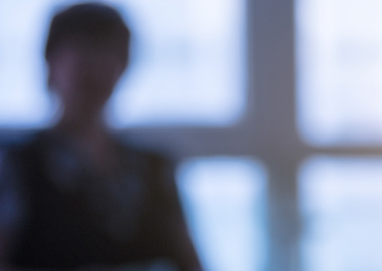 An out of foucs image of a female in a conference room with windows