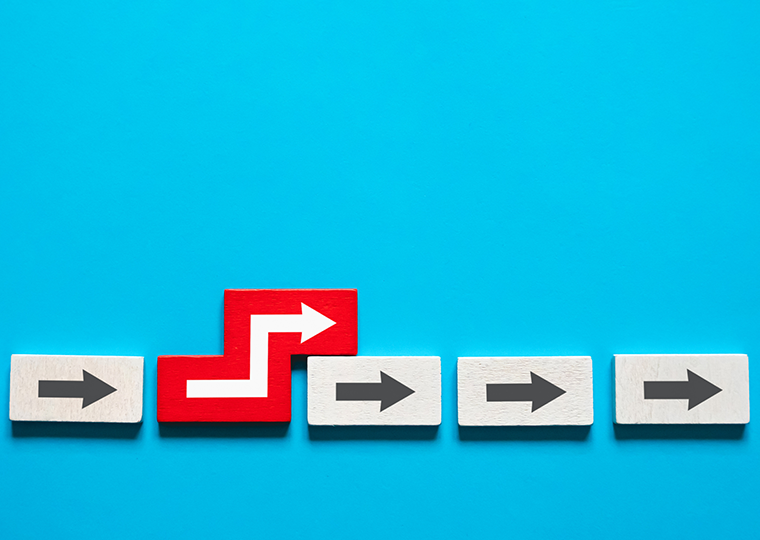 White tiles with arrows pointed right lined up on a blue background with one red tile that shoes the arrow moving out of the line.
